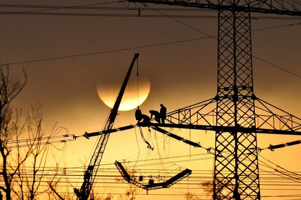 Imagen los electricistas trabajan en altura al atardecer