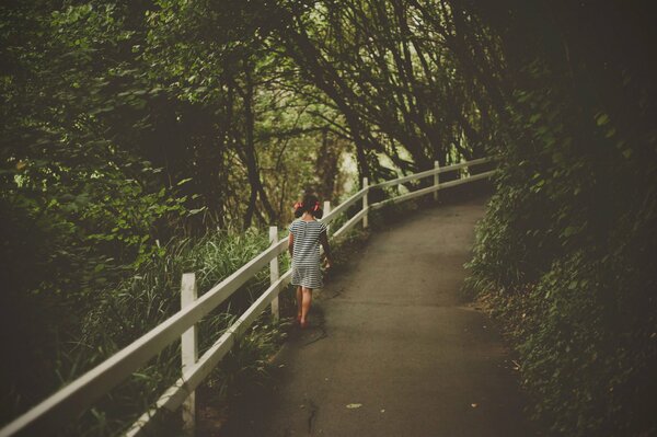 Niña caminando por el camino del bosque