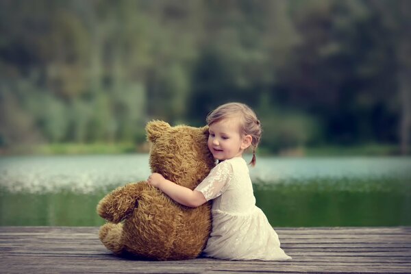 Fille avec un ours en peluche sur le lac