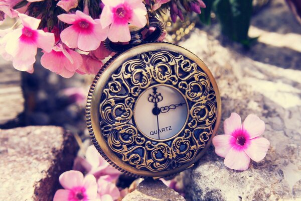 Reloj en un grabado caro junto a las flores