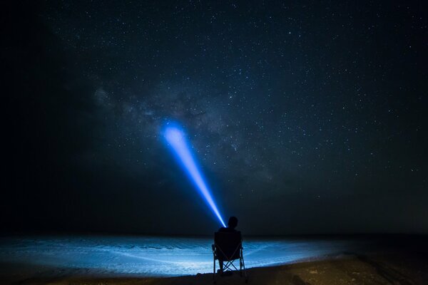 El hombre brilla una linterna en el cielo estrellado