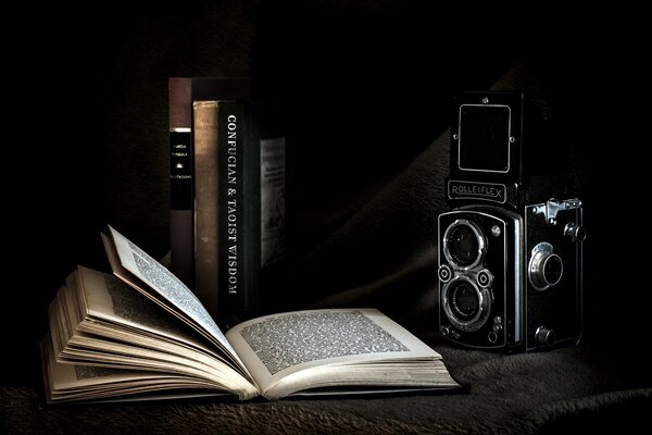 An open book on the background of a camera and books