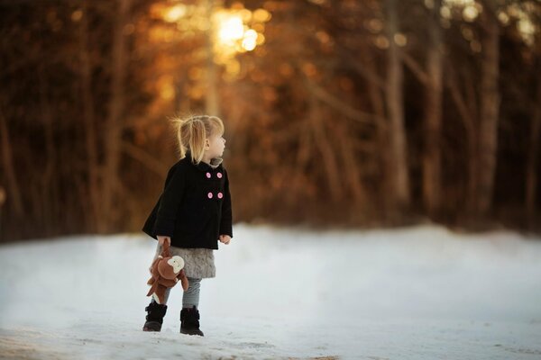 A girl with a toy on a snowy road