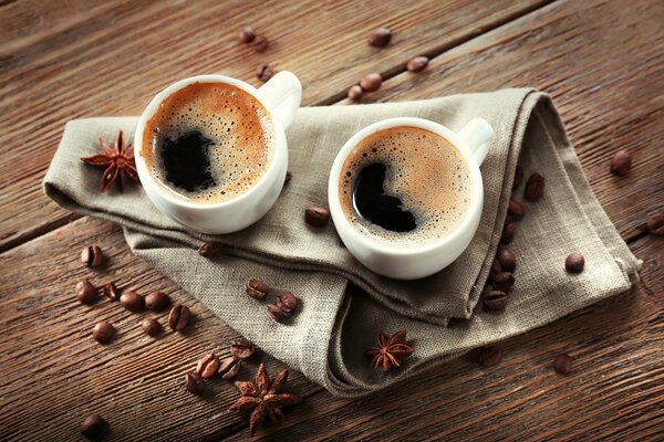 2 tazze di caffè su un tovagliolo intorno chicchi di caffè