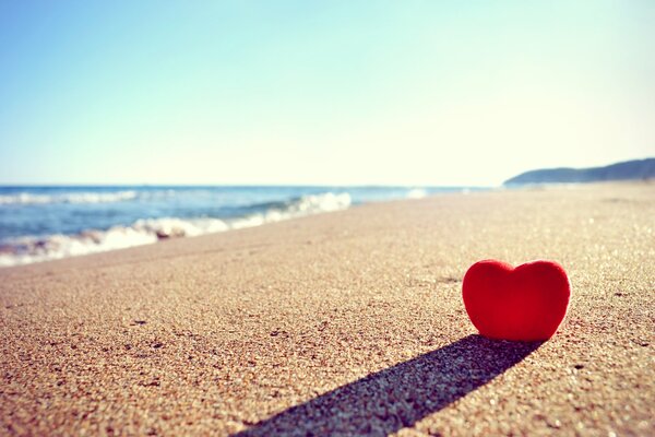 The red heart is buried in the sand on the beach