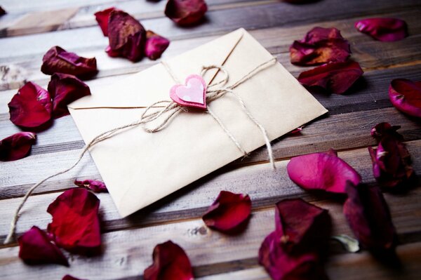 The envelope is lying on the table surrounded by rose petals