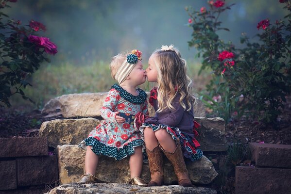 Cute girls kissing on the background of stones and flowers