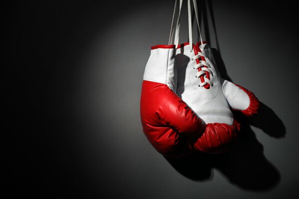 Guantes de boxeo rojos y blancos colgados en la pared negra