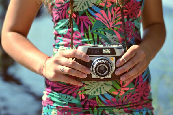 An old camera with a strap in the hands of a girl