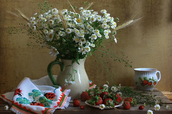 A vase of daisies on a stand with a cup and a plate of strawberries