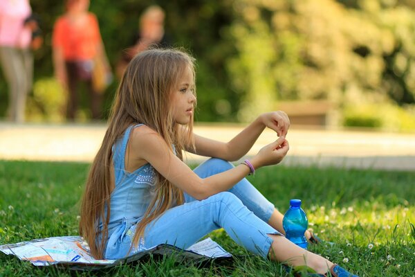 A young model with beautiful hair poses on the grass