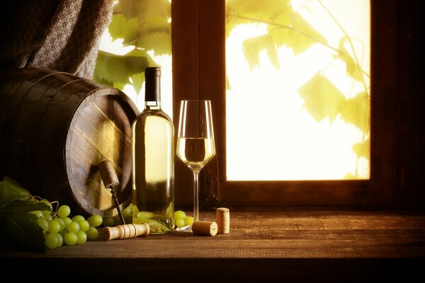 Auf der Fensterbank stehen Wein, ein Glas, Trauben und ein Fass