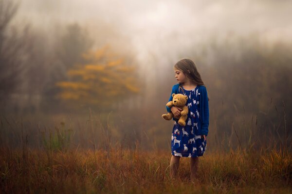 Ragazza con orso nella foresta nebbiosa