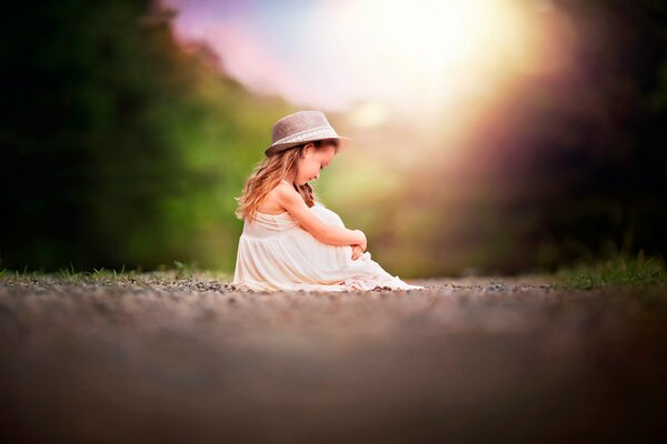 La ragazza si siede sul suo cappello bokeh