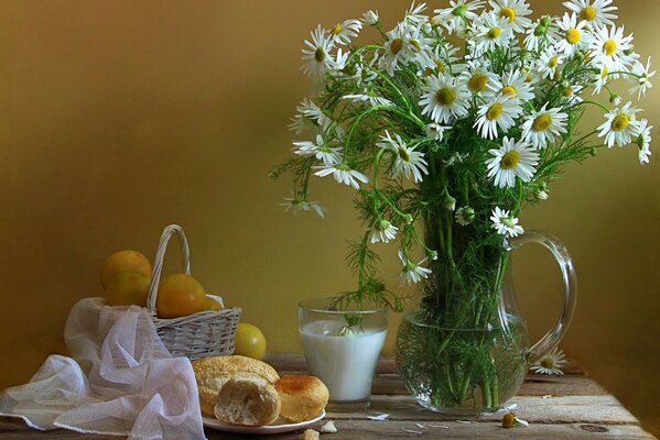 A bouquet of daisies in a decanter and food on the table