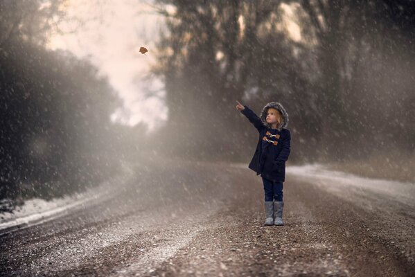 Niña de pie en el camino de otoño