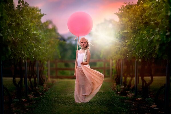 A girl with a pink balloon in nature