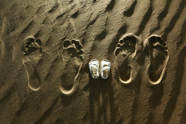 Footprints of parents and child s shoes in the sand