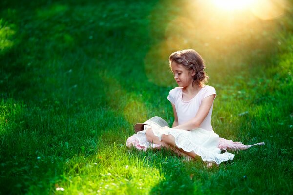 A girl in a white dress in a green clearing