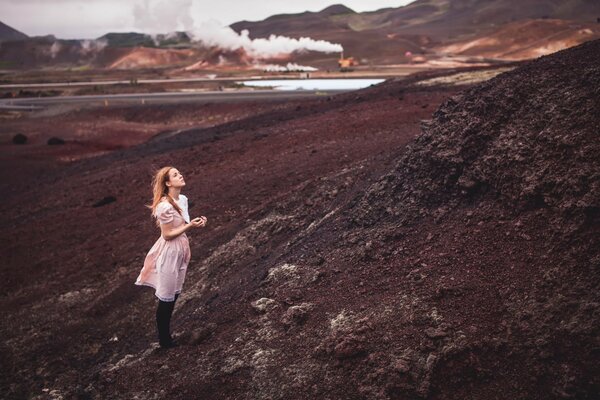 A girl climbs a mountain in a dress