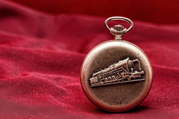 Pocket watch on a red background with a picture of a locomotive