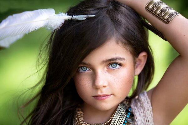 Niña con ojos verdes y cabello oscuro con una pluma