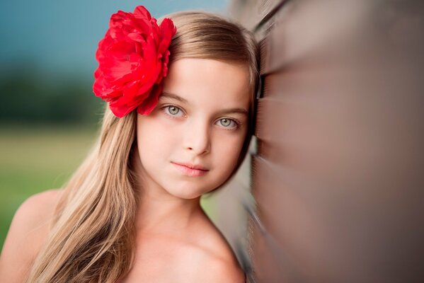 Hermosa chica rubia con una rosa en el pelo