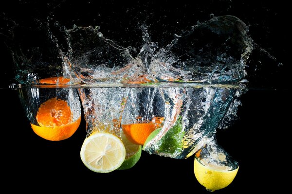 Cítricos en salpicaduras de agua sobre un fondo negro