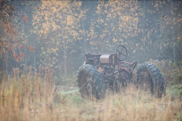 Tractor en el fondo del otoño en la niebla