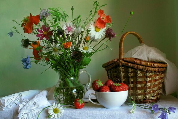 Pichet, fraise et panier debout sur la table contre le mur