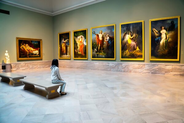 Jeune fille assise dans le musée et examine les peintures