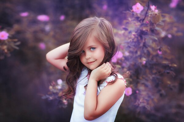 Hermosa chica en el fondo de las flores púrpuras