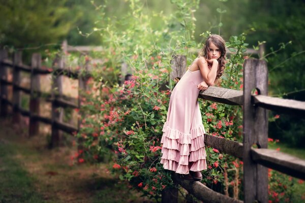 A girl in pink on the background of a wooden fence