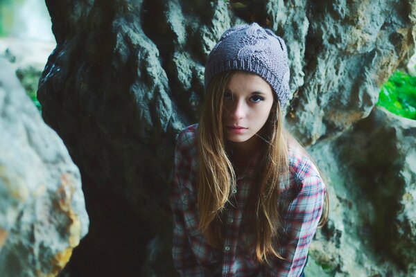 A girl in a hat and shirt on the background of rocks