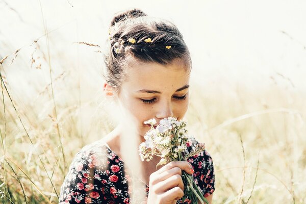 La ragazza di estate nel campo annusa il bouquet