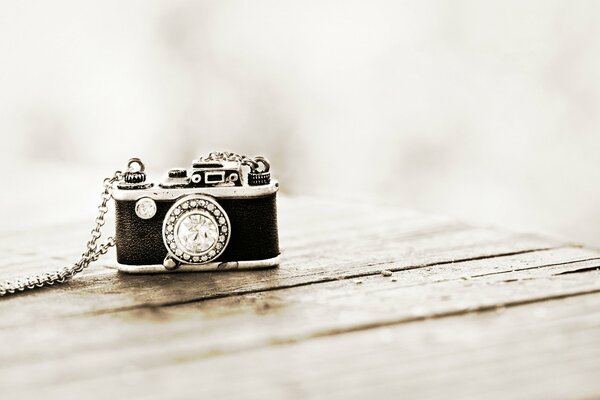 An old camera with a chain on a wooden table out of focus