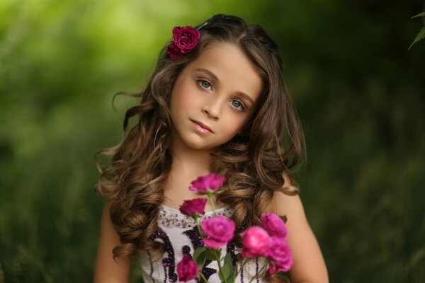 Portrait of a girl with roses on a background of foliage