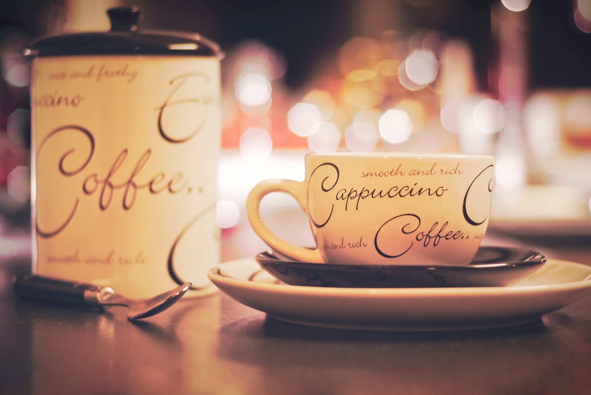 tazza piattino piatto zuccheriera lettering cappuccino caffè cucchiaio tavolo bokeh