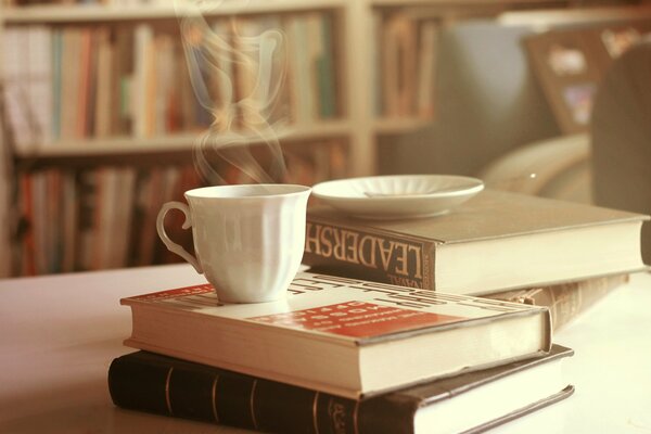 Heißer Tee mit Büchern auf dem Tisch helles Foto