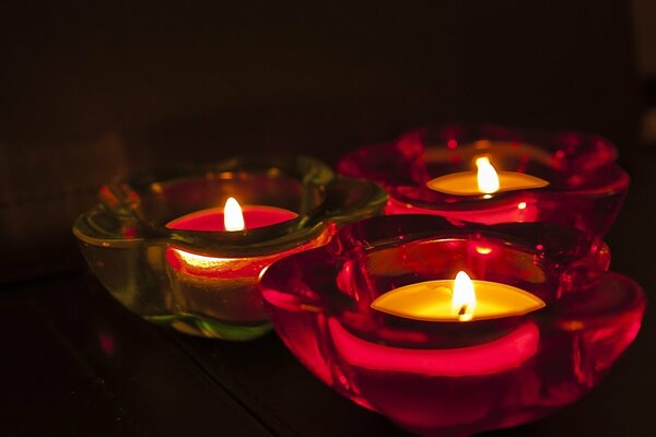 Three candles are burning in glass candlesticks