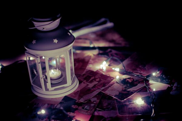 A lantern on the table with photos and a garland