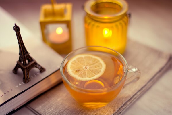 Sur la table se trouvent une tasse de thé au citron tour Eiffel et des bougies