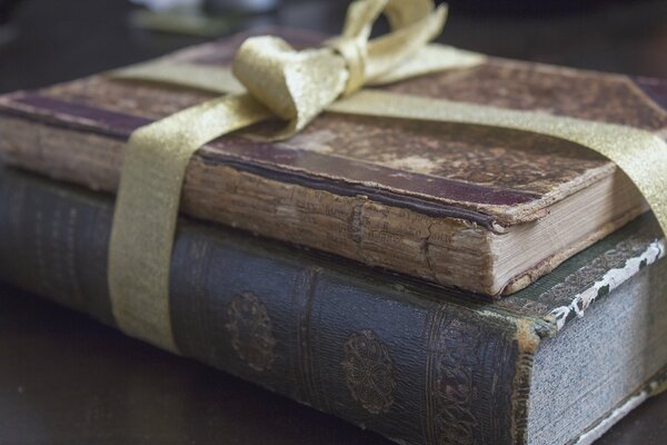 Two old books are tied with a ribbon in a bow