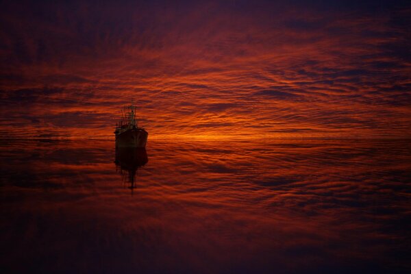 Barco y nubes en reflexión al atardecer