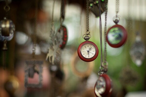 A watch on a chain hangs on a blurry background