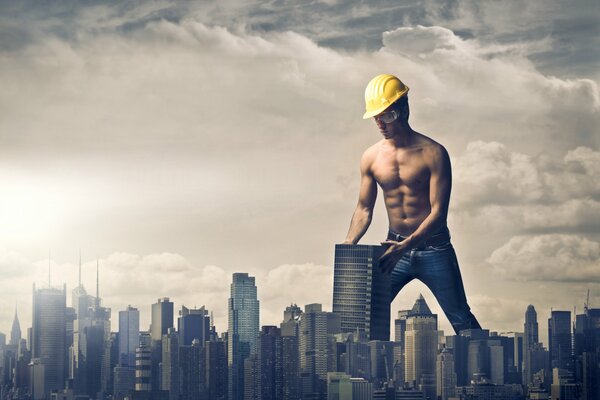 Un homme en géant dans un casque construit une ville sous les nuages