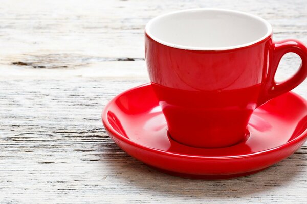 A red cup with a saucer on a wooden surface