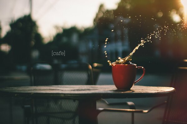 Splash of coffee in a cup on the table of an outdoor cafe