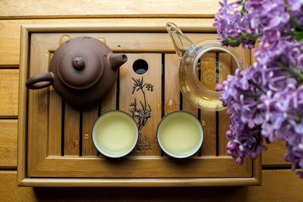 Tea drinking from a clay teapot surrounded by lilac