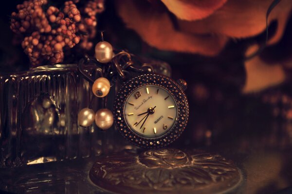 Belle horloge en métal avec des perles sur la table avec des fleurs